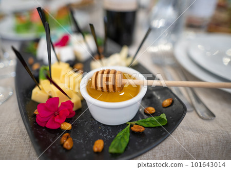 a dish of various delicious cheeses and a plate of honey. 101643014