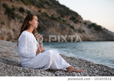 A girl on the seashore in a white dress holds an ancient key in her hands. 101643618