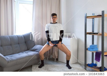 Funny nerd young man in glasses is performing simple dance movements at home. 101643863