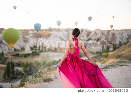 a girl in a flying dress with a long train on the background of balloons in Cappadocia. 101643910
