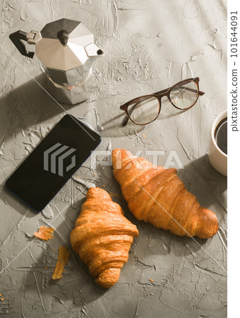 Breakfast with croissant and coffee and moka pot and smartphone with eyeglasses. Morning meal and breakfast concept. 101644091