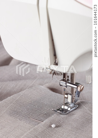 Modern sewing machine presser foot with linen fabric and thread, closeup Modern sewing machine presser foot with linen fabric and thread, closeup 101644173