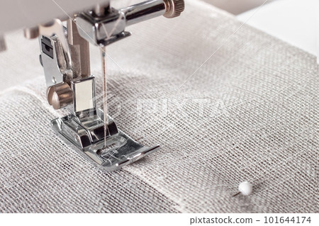 Modern sewing machine presser foot with linen fabric and thread, closeup Modern sewing machine presser foot with linen fabric and thread, closeup 101644174