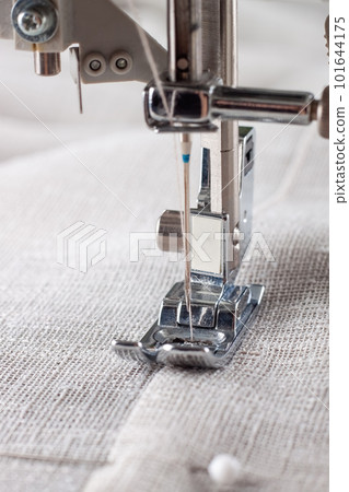 Modern sewing machine presser foot with linen fabric and thread, closeup Modern sewing machine presser foot with linen fabric and thread, closeup 101644175