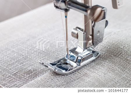Modern sewing machine presser foot with linen fabric and thread, closeup Modern sewing machine presser foot with linen fabric and thread, closeup 101644177