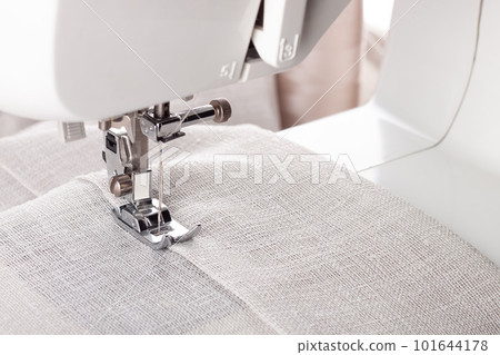 Modern sewing machine presser foot with linen fabric and thread, closeup Modern sewing machine presser foot with linen fabric and thread, closeup 101644178