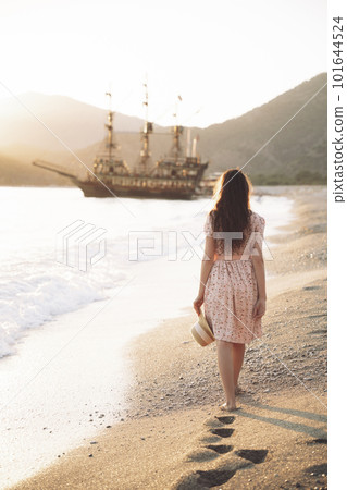 beautiful sexy girl in a dress walks on the beach against the background of ships. 101644524