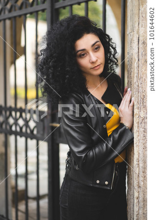 a beautiful girl in a leather jacket poses against the background of the city. 101644602