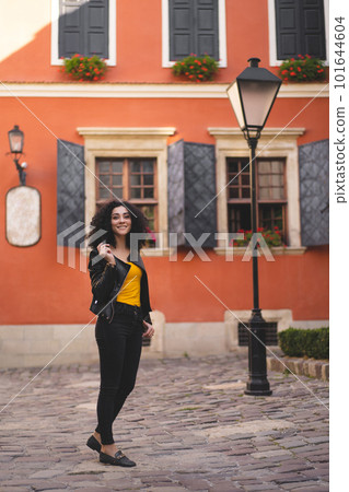 a beautiful girl in a leather jacket poses against the background of the city. 101644604