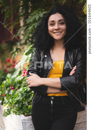 a beautiful girl in a leather jacket poses against the background of the city. 101644605