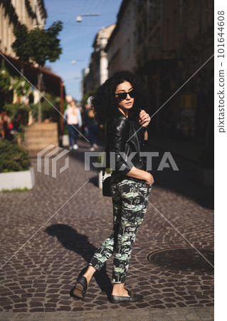 a beautiful girl in a leather jacket poses against the background of the city. 101644608