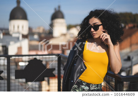 a beautiful girl in a leather jacket poses against the background of the city. 101644609