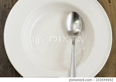 White plate and spoon on wooden table White plate and spoon on wooden table 101644942