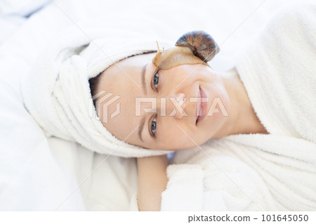 Female doing snail facial procedure after massage on bed 101645050