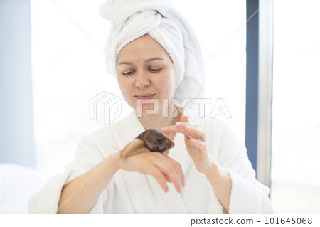Lady holding snail on arm as skincare procedure at home Lady holding snail on arm as skincare procedure at home 101645068