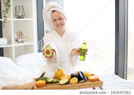 Woman showing avocado and skincare remedy in bedroom Woman showing avocado and skincare remedy in bedroom 101645361