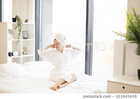 Female stretching limbs on bed in studio apartment Female stretching limbs on bed in studio apartment 101645430