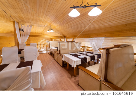 The interior of the restaurant in the style of wood, with a large table and chairs. The interior of the restaurant in the style of wood, with a large table and chairs. 101645619