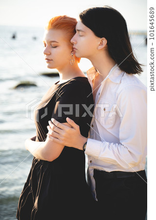 two lovers boy and girl are happy walking and hugging on the sandy beach near the sea. two lovers boy and girl are happy walking and hugging on the sandy beach near the sea. 101645689