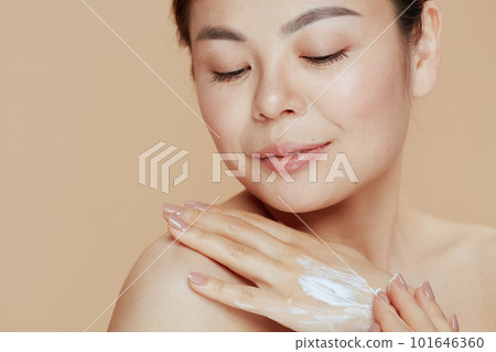 relaxed modern woman with hand cream on beige background 101646360