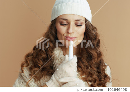 smiling trendy woman in beige sweater, mittens and hat 101646498