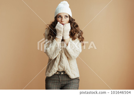 stylish woman against beige background warming hands 101646504