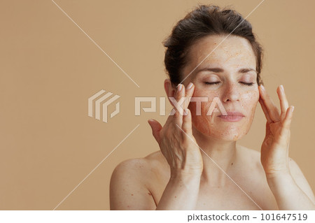 young woman with face scrub isolated on beige 101647519