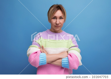 confident blond young woman in a striped sweater crossed her arms in front of her on a blue 101647703