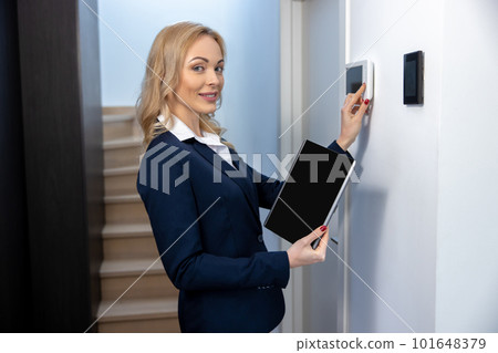 Pleased woman adjusting the electronic equipment in the smart house 101648379