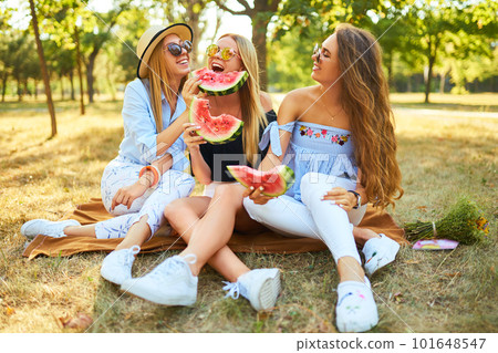 Three nice girls having fun eating watermelon In the park. Excellent sunny weather. Beautiful figures Three nice girls having fun eating watermelon In the park. Excellent sunny weather. Beautiful figures 101648547