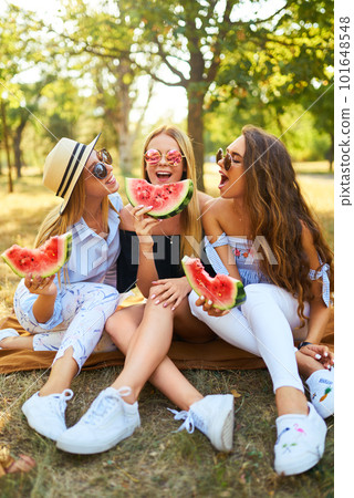 Three nice girls having fun eating watermelon In the park. Excellent sunny weather. Beautiful figures Three nice girls having fun eating watermelon In the park. Excellent sunny weather. Beautiful figures 101648548