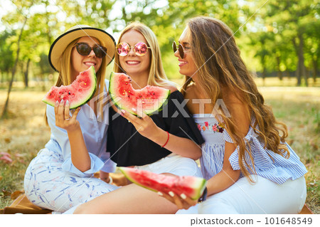 Three nice girls having fun eating watermelon In the park. Excellent sunny weather. Beautiful figures Three nice girls having fun eating watermelon In the park. Excellent sunny weather. Beautiful figures 101648549