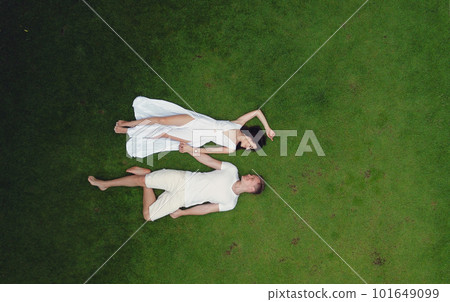 Couple on vacation. People on lie on a grass. Lady in a white dress. Shooting from a drone. Couple on vacation. People on lie on a grass. Lady in a white dress. Shooting from a drone. 101649099