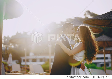 beautiful young long-haired bride in white dress with her young husband on the beach 101649143