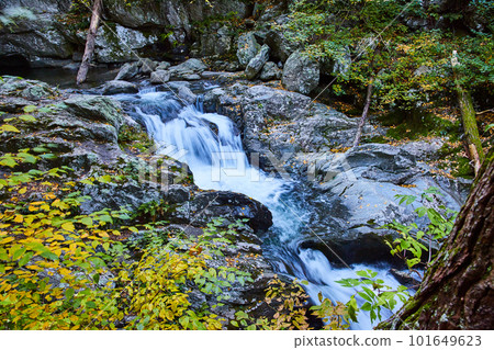 Yellow foliage and rocks surround river with cascading waterfalls in New York 101649623