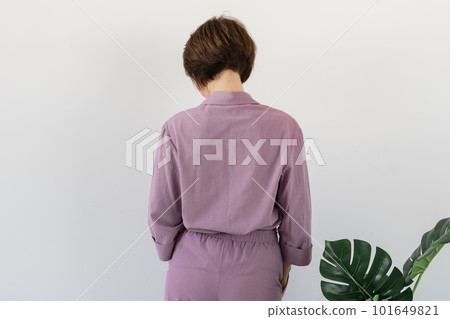Back view of woman dressed in beautiful colorful pajama posing as a model in her living room. Comfortable sleepwear, home relaxation and female fashion concept. 101649821