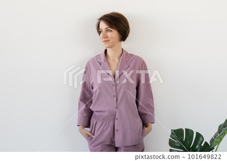 Young attractive woman dressed in beautiful colorful pajama posing as a model in her living room. Comfortable sleepwear, home relaxation and female fashion concept. 101649822