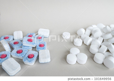 White pressed salt tablets and colored dishwasher capsules close-up. Place for text White pressed salt tablets and colored dishwasher capsules close-up. Place for text 101649956