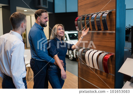 The seller helps a married couple choose the color of a new car. The seller helps a married couple choose the color of a new car. 101653083