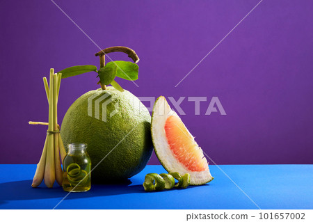 A pink pomelo (Citrus maxima) and essential oil extracted from lemongrass and pink pomelo contained inside a glass jar decorated on colorful background. Promotion of hair care or skincare product A pink pomelo (Citrus maxima) and essential oil extracted from lemongrass and pink pomelo contained inside a glass jar decorated on colorful background. Promotion of hair care or skincare product 101657002