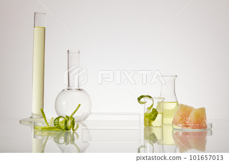 Front view of scientific glassware with essential oil inside of pink pomelo (Citrus maxima) extract. Empty transparent podium to promote product. Front view of scientific glassware with essential oil inside of pink pomelo (Citrus maxima) extract. Empty transparent podium to promote product. 101657013