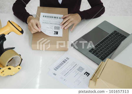 Young business owner putting shipping label on parcel. 101657313