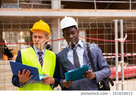 Architect and foreman must write documents and drawings on laptop with building construction Architect and foreman must write documents and drawings on laptop with building construction 101658015