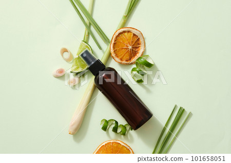 Top view of brown bottle without label, lemongrass, lemon and dried orange pieces on light background. Mockup for cosmetic product of natural herbal extract. Essential oils good for health and hair. 101658051