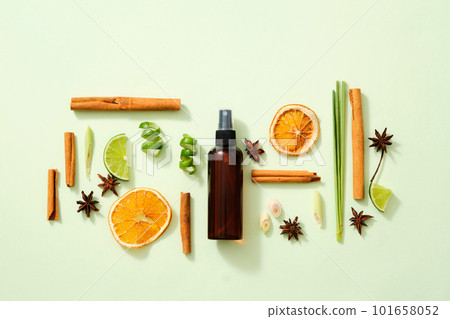 Scene mockup for product of natural flavoring extract with brown bottle without label, cinnamon sticks, illicium verum, lemon slice, dried orange slices and lemongrass on light background. Top view 101658052