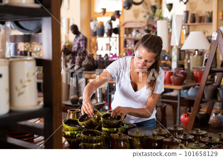 Female buyer chooses ceramic dishes and decorative items in a store Female buyer chooses ceramic dishes and decorative items in a store 101658129