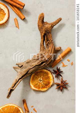 Flat lay of cinnamon sticks, star anise and dried orange slices with a big tree branch decorated on light background. Healthy lifestyle concept. Empty area for text or product advertisements 101658141