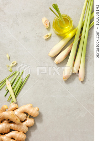 A glass jar containing essential oil extracted from lemongrass. over a minimalist background, some gingers and lemongrass are displayed. Empty space for text or product adding 101658143