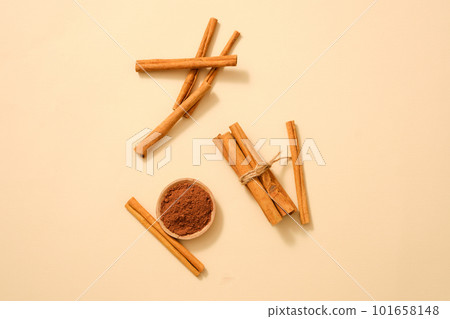 Many cinnamon sticks are displayed with cinnamon powder on a light background. Cinnamon (Cinnamomum) essential oil has a lot of benefits for health 101658148