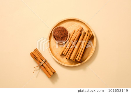 A wooden dish with cinnamon sticks and cinnamon powder placed on. Cinnamon (Cinnamomum) is usable for cooking, healing and ingredient for cosmetic 101658149